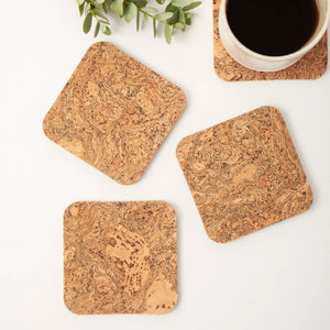 Set of four Liga natural cork coasters beside a cup of coffee.