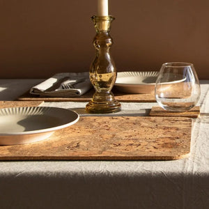 Natural cork placemat set on a table with glassware and brass candlestick.