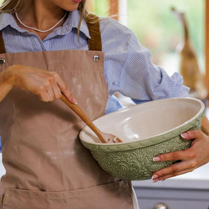 Person in a kitchen holding a the Mason Cash Home To Roost Hen Mixing Bowl in Green (29cm).
