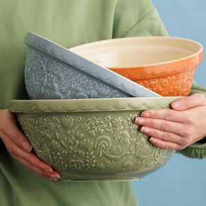 Person holding three of the Mason Cash Home To Roost Hen Mixing Bowls against a blue background.