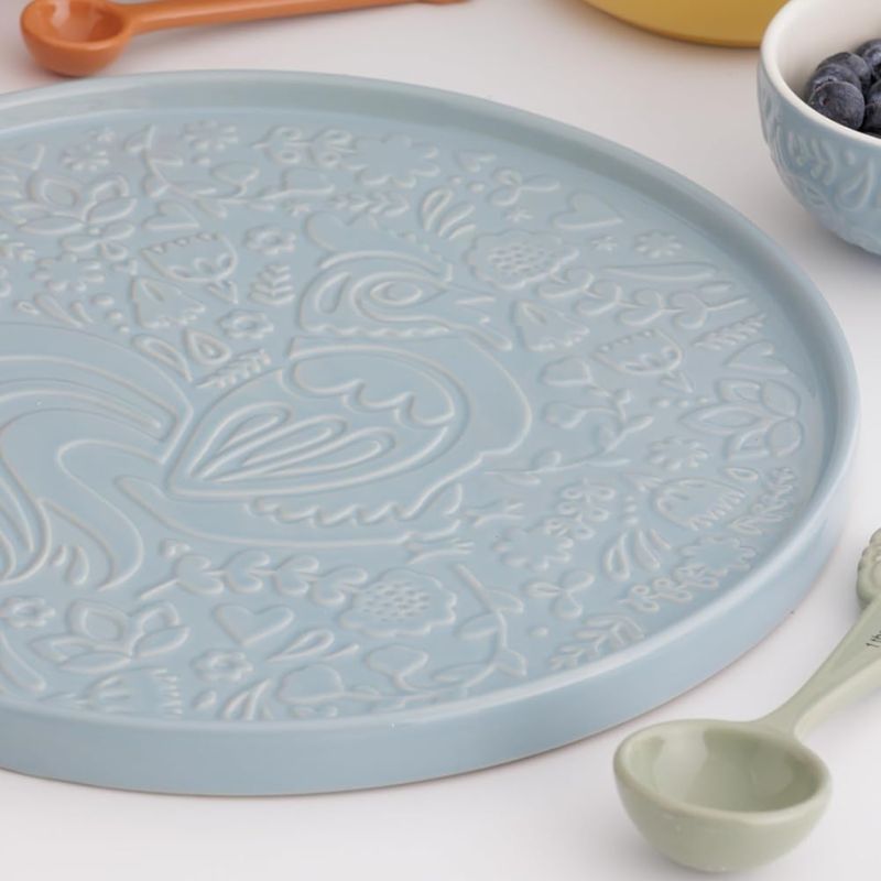 Blue Mason Cash round platter on a table with matching bowl and mug, showcasing embossed pattern.