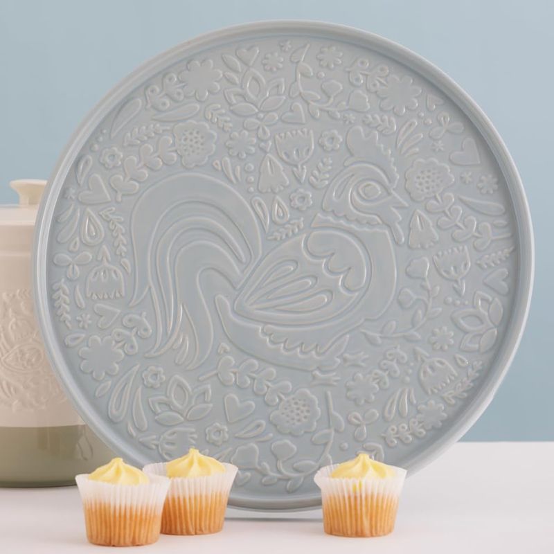 Detailed view of Mason Cash Home to Roost platter showing embossed rooster design, with cupcakes in the foreground.