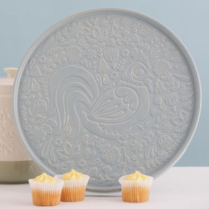 Detailed view of Mason Cash Home to Roost platter showing embossed rooster design, with cupcakes in the foreground.