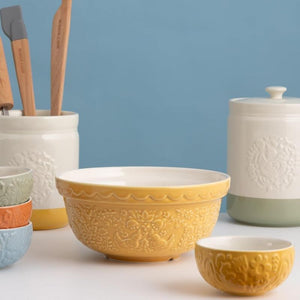 Mason Cash Home To Roost Hen Mixing Bowl in Yellow next to other ceramic mixing bowls against a light blue background.