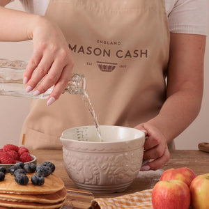 Person pouring water into the Mason Cash In The Forest Fox Measuring Jug in Stone on a kitchen counter with fruits and pancakes.