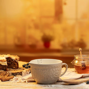 Mason Cash In The Forest Fox Measuring Jug in Stone on a wooden table, surrounded by cake, honey and cinnamon sticks.