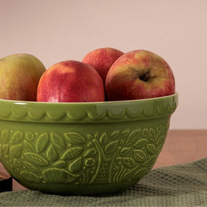 Mason Cash In The Forest Green Hedgehog Mixing Bowl containing red apples on a neutral background