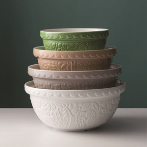 Stack of four Mason Cash In the Forest ceramic mixing bowls on a dark background.