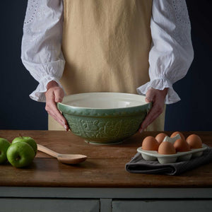 Person holding the Mason Cash In The Forest Owl Mixing Bowl in Dark Green (26 cm) styled next to eggs and apples.