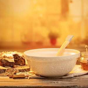 Stone coloured Mason Cash In The Forest Owl Mixing Bowl on a rustic kitchen bench with cake and honey.