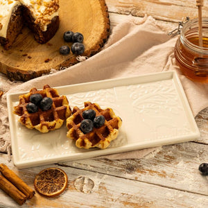 Mason Cash In The Forest Serving Platter, surrounded by cinnamon sticks and a jar of honey on a wooden surface.