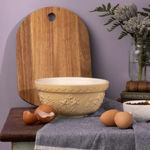 Yellow Mason Cash In The Meadow mixing bowl on a bench with eggs and wooden board