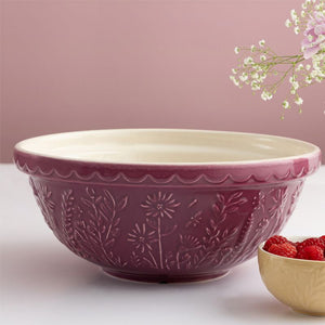 Purple Mason Cash Daisy mixing bowl on a pink background with raspberries