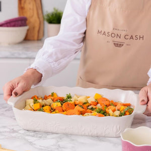 Person holding the Mason Cash In The Large Meadow Rectangular Oven Dish filled with chopped vegetables.