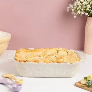 Mason Cash In The Meadow Medium Rectangular Oven Dish shown on a pink background filled with pie.