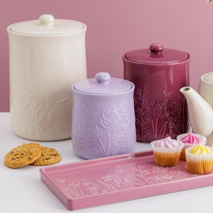 Set of Mason Cash In The Meadow Storage Jars and a tray with floral patterns on a pink background