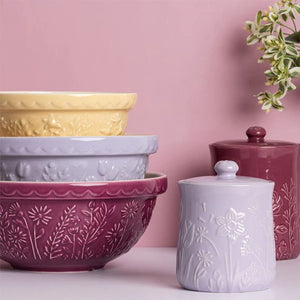 Set of Mason Cash In the Meadow ceramic bowls and storage jars with floral patterns on a pink background