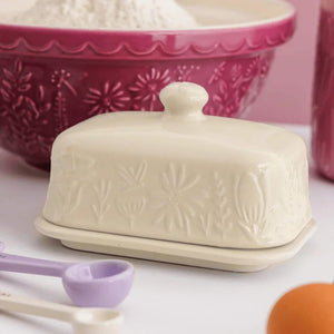 Mason Cash In The Meadow Cream Butter Dish on a counter beside a pink mixing bowl and measuring spoons.