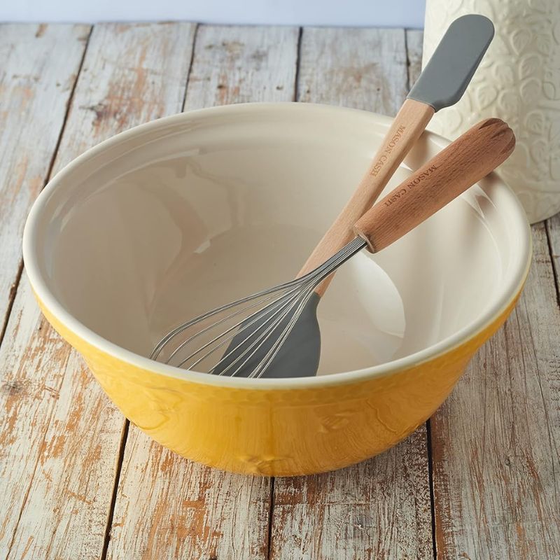 Inside view of Mason Cash Sweet Bee Yellow Mixing Bowl with whisk on rustic wood table.