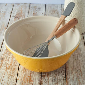 Inside view of Mason Cash Sweet Bee Yellow Mixing Bowl with whisk on rustic wood table.