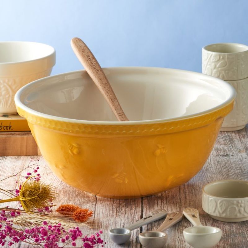 Yellow Mason Cash Sweet Bee Mixing Bowl styled with wooden spoon, measuring cups and spoons in a rustic kitchen.