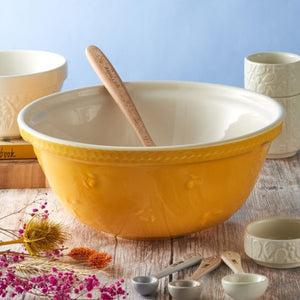 Yellow Mason Cash Sweet Bee Mixing Bowl styled with wooden spoon, measuring cups and spoons in a rustic kitchen.