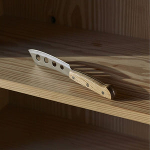 Morso cheese knife with oak handle resting on a wooden shelf.
