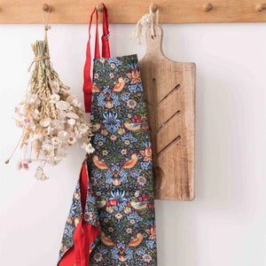 Museums & Galleries Strawberry Thief apron hanging from a wooden rack by the red adjustable neck strap.