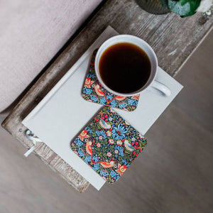Two William Morris Strawberry Thief coasters with cup of coffee.