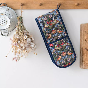 Museums & Galleries Strawberry Thief double oven mitt hanging on a wooden hook next to dried flowers, with a white wall background.