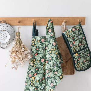 V&A Dearle Designs tea towel with matching oven glove and apron hanging in a kitchen.