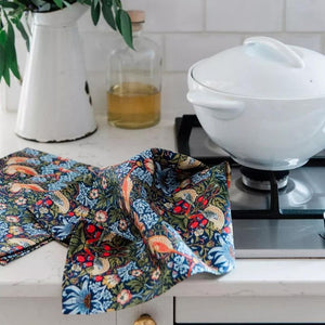 V&A Morris Designs Strawberry Thief tea towel draped beside a white casserole dish.