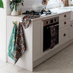 V&A Morris Designs tea towels hanging in a kitchen alongside the William Morris Strawberry Thief double oven glove.