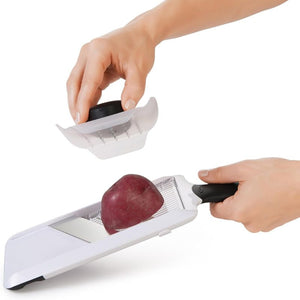 Person slicing a potato using the OXO Good Grips Hand Held Mandoline Slicer with underside of the safety guard shown.