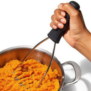 Hand using a the OXO Good Grips Wire Potato Masher to mash sweet potatoes in a pot.