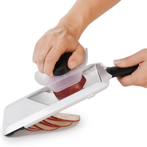 Person slicing a potato using the OXO Good Grips Hand Held Mandoline Slicer on a flat surface.
