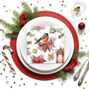 PAW Paper Napkins in the Bullfinch with Lampion design styled on a white plate over a red place mat with holiday greenery, candy cane, glass, and silverware.