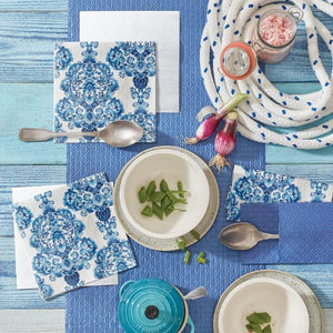 PAW Porcelain Ornament Paper Napkins styled on a blue wooden table with cutlery and chives.