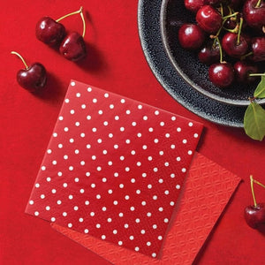 PAW Red Dots Paper Napkins styled next to cherries on a red table.