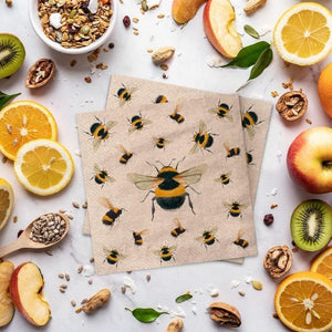 PAW We Care Dancing Bees Paper Napkins styled on a table with fruit and nuts.