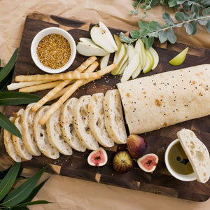 Peer Sorensen End Grain Cutting Board with sliced bread, pears, figs, and a small bowl of seeds on a rustic background.