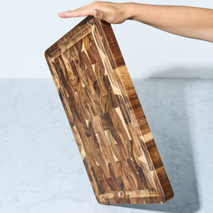 Peer Sorensen End Grain Cutting Board with Juice Groove held by a hand on a light grey background