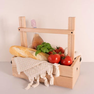 Wooden picnic table turned into a basket with handle, styled with bread, tomatoes, and produce