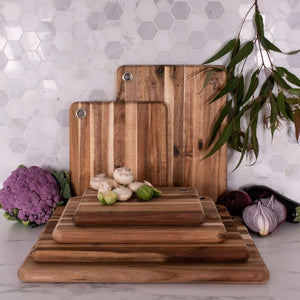 Set of Peer Sorenson long grain acacia chopping boards styled with vegetables and herbs on a bench top.