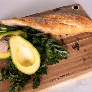 Acacia chopping board styled with bread, avocado, and fresh herbs