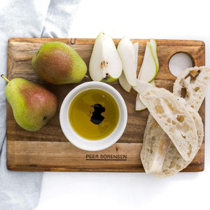 Medium sized Peer Sorensen Long Grain Cutting Board styled with pears, bread, and olive oil