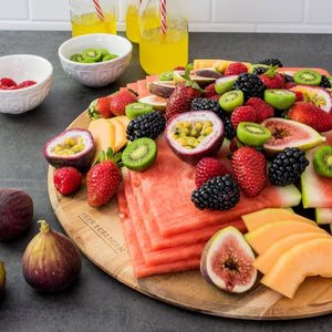 Close up of Peer Sorensen Round Paddle Board topped with fresh fruit including watermelon, figs, berries, and kiwifruit