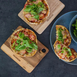 Small serving boards topped with toasted pita breads alongside a plate of food.