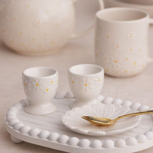 Price & Kensington Daisy Egg Cup Set styled on a white tray next to a gold spoon.