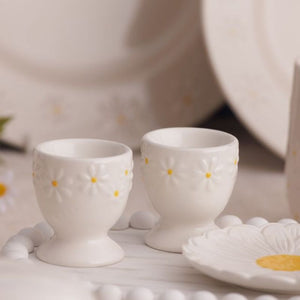 Price & Kensington Daisy Egg Cup Set styled on a light tabletop with matching white dishes in the background.
